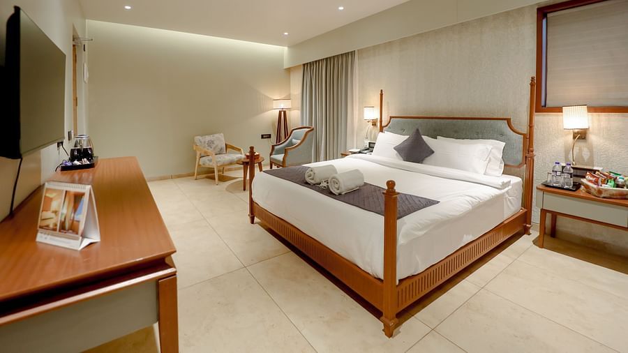 An image of a villa with king size bed, bedside table with lamp, a flat TV screen and other essentials - Pride Resort Ambaji